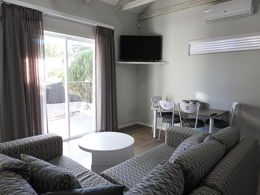 Air-conditioned family holiday accommodation in Oudtshoorn with a flat-screen TV layout and sliding door patio access for large tour groups, school excursions, and holidaymakers.