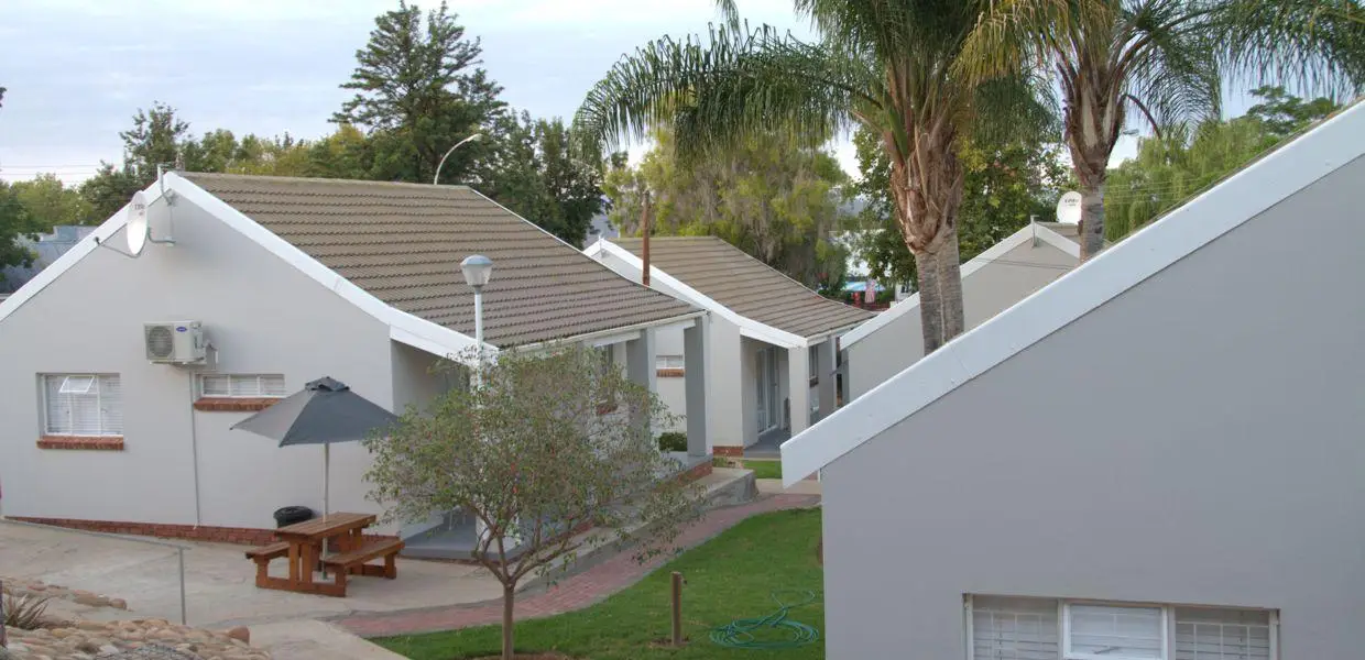 White self-catering units set in the garden at The Featherbed, Oudtshoorn