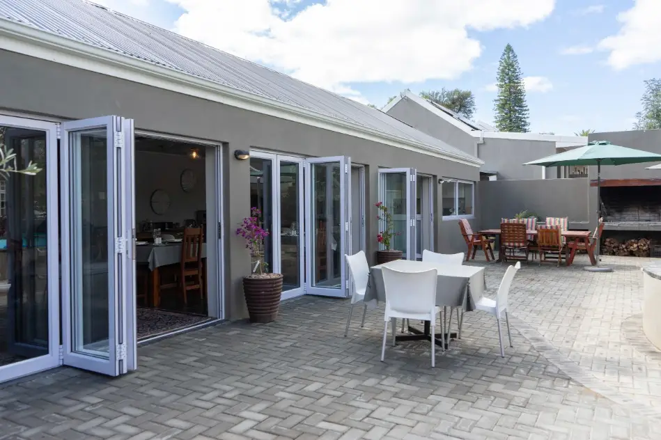 Outdoor paved courtyard patio with dining tables and built-in braai facilities at a secure group accommodation estate in Oudtshoorn.