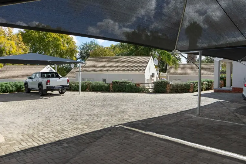 Secure undercover parking bays with shade cloth carports and brick paving at a group guest lodge estate in Oudtshoorn.